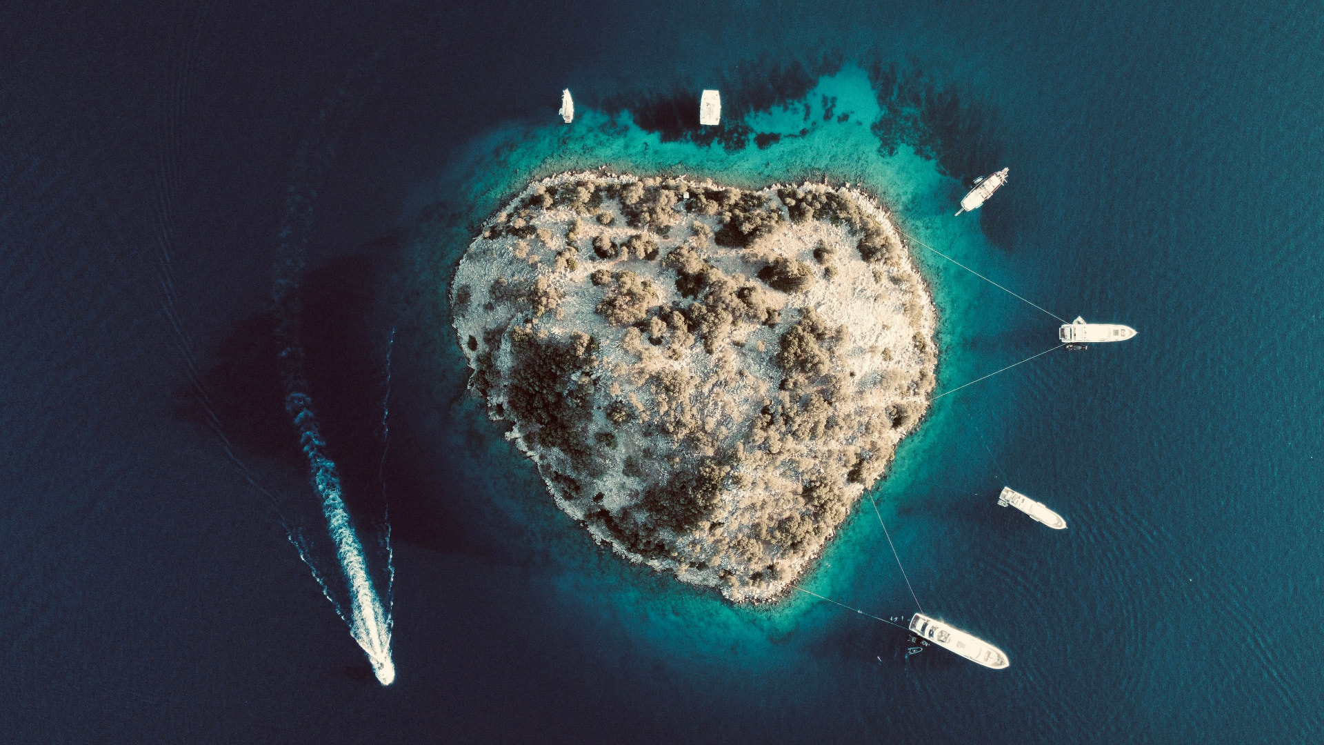 Aerial view of a small Adriatic island with yachts anchored around it