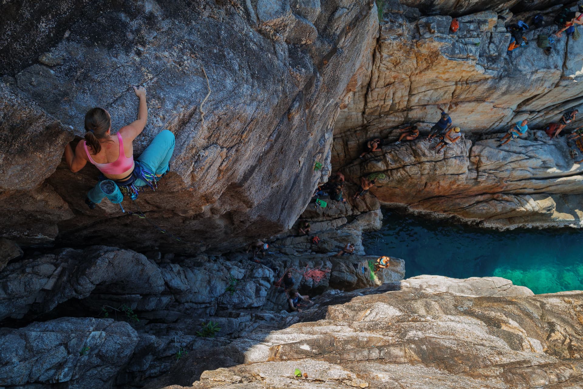 Climber on a coastal cliff above emerald sea